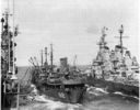 By the end of World War II, refueling at sea was being conducted on a routine basis and had progressed to the point where two large warships could be serviced at the same time. This maneuver was not as easy as it may appear as there was always the risk that the oiler would be crushed by the two larger ships. Here Cahaba (AO-82)--shown 8 July 1945--refuels Shangri-La (CV-38) on her port side and Iowa (BB-61) on her starboard side. Note the calmness of the seas and the critically small distance between ships. (National Archives) 